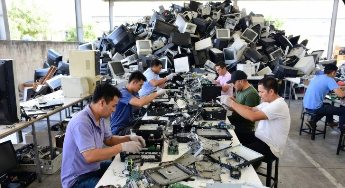 Technicians dismantling electronics at work tables